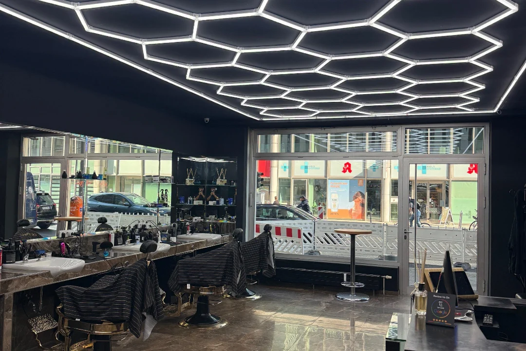Heller Innenraum des Berberlin mit Barber-Chairs, Marmor-Konsolen und Hexagon-Licht