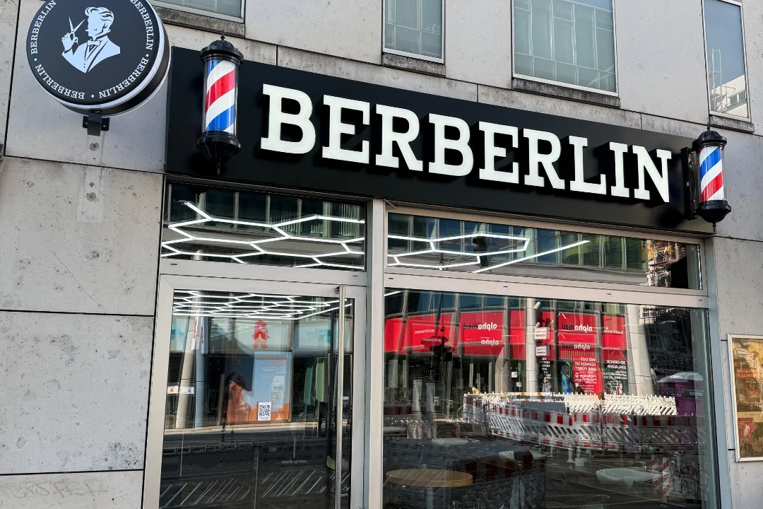 Ladenfront des Berberlin an der Rudi-Dutschke-Straße mit Leuchtschriftzug und zwei Barber-Poles